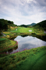 Fototapeta premium 울창한 숲과 연못에 둘러싸인 골프장 풍경.