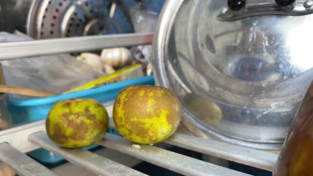 Woman hand pick up rotten lime from  silver shelf in kitchen and put fresh cut lime back on shelf.