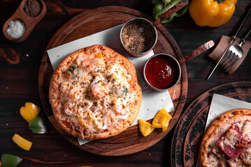 shrimp pizza topped with cheese on a wooden cutting board, with oregano and paprika as a backdrop. This is a pizza that is perfect for sharing with friends.
