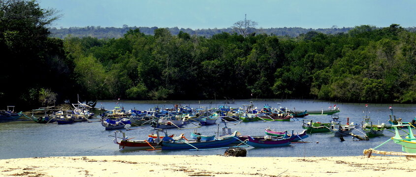 gesch&uuml;tzter Fischerhafen beim Pero Beach mit vielen Holzbooten am Sandigen Ufer vor gr&uuml;nem Wald auf der Insel Sumba in Indonesien