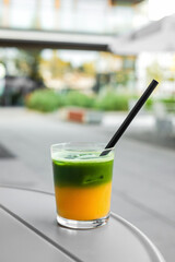 Two layered matcha with orange juice in a glass