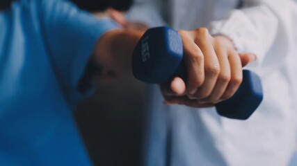 Young pretty asian physiotherapist helping senior female patient holding dumbbell in physical therapy session, concept of World Confederation for Physical Therapy.