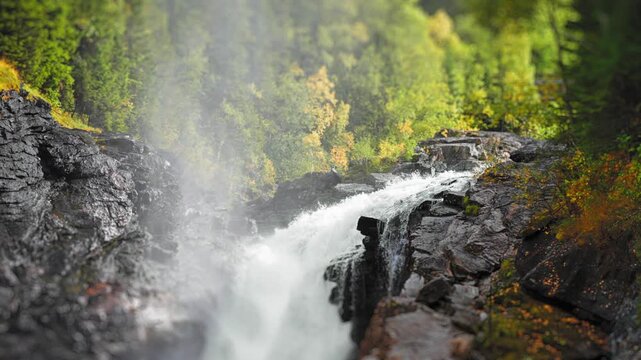 A picturesque close-up of a waterfall in the autumn forest cascading over jugged stones, highlighting the dynamic flow and seasonal colors
