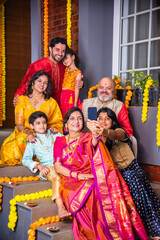 Naklejka premium Indian family in traditional attire taking a group selfie on steps in Diwali or festival celebration