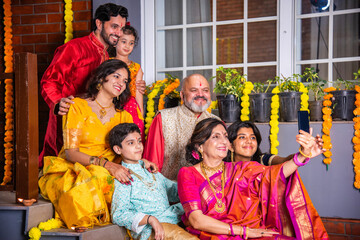 Indian family in traditional attire taking a group selfie on steps in Diwali or festival celebration