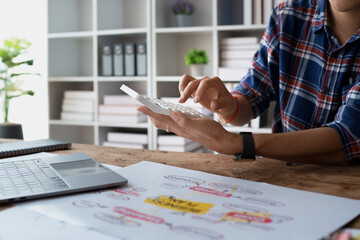 man meticulously plans a finance audit, using a computer and calculator to review budget documents...