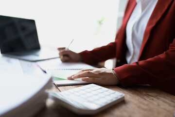 woman meticulously plans a finance audit, using a computer and calculator to review budget...