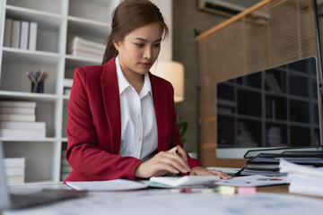 woman meticulously plans a finance audit, using a computer and calculator to review budget...