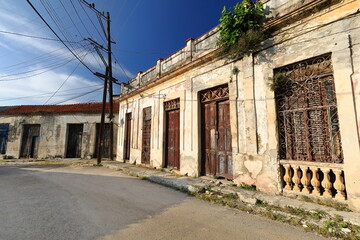 Fototapeta premium One-storey Colonial townhouses of paint-faded chipped facades, damaged wooden doors and rusty grille windows, Calle Santuario Street. Havana-Cuba-640