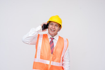 A construction project manager or engineer in a safety helmet and vest talking to a colleague over his cellphone. Isolated on a white background.