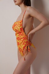 A beautiful slender girl in a orange one-piece swimsuit in a Moroccan-style sand studio. A pretty...