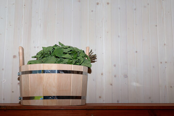 Wooden bucket with an oak broom for steaming. Traditional Russian bathhouse, sauna, banya. Copy...