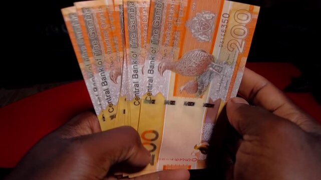 One male black hand holding spread new 200 Dalasi cash notes and packed later