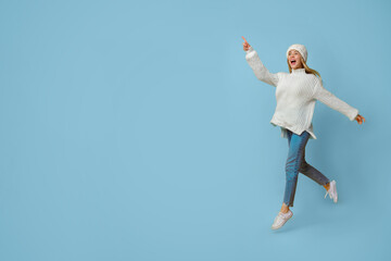 Magnetic offer. Excited winter girl pointing and running towards copy space, yellow background