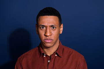 Portrait of young man sad face wear brown shirt isolated on dark blue color background