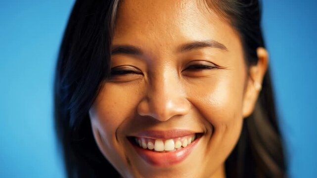 Smiling woman with dimples against a blue background