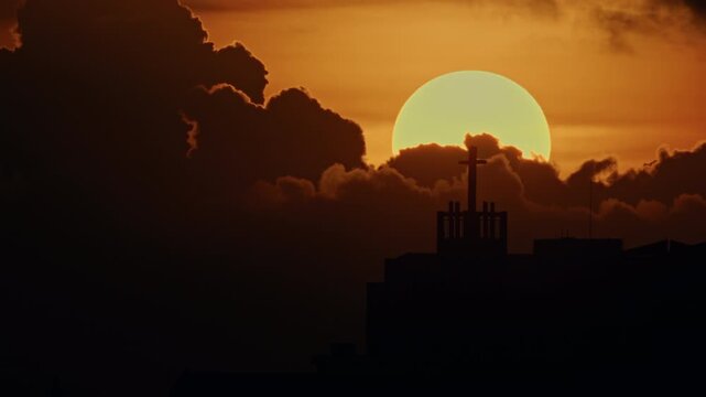 crucifix in backlight, sun behind the crucifix that appears creating rays of light, background clouds