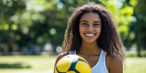 Naklejka premium A woman with long hair is smiling and holding a yellow soccer ball. Concept of joy and playfulness, as the woman is enjoying herself while holding the ball