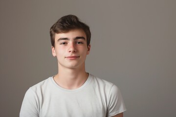 Happy young man in a casual t-shirt, exuding confidence and cheerfulness in a studio portrait.