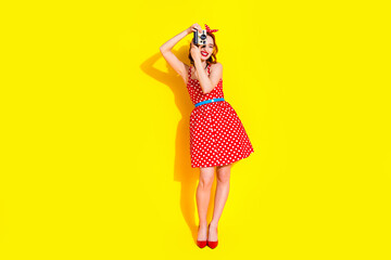 Photo of cute cheerful lady wear red stylish clothes hold camera take picture isolated on yellow color background