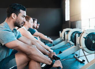 Fitness, gym and man on rowing machine for health, wellness and body workout in class. Exercise,...
