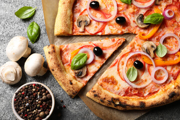 Cut delicious vegetarian pizza and ingredients on grey table, flat lay