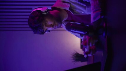 Vertical video: The participants of the special game are completely immersed in the game session using the joystick and speaking into the microphone. The ambient lighting creates a vibrant atmosphere