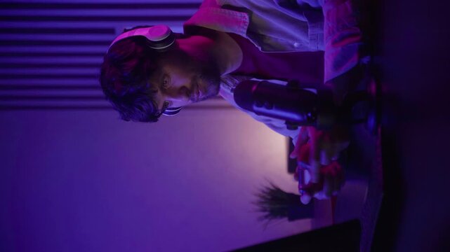 Vertical video: The participants of the special game are completely immersed in the game session using the joystick and speaking into the microphone. The ambient lighting creates a vibrant atmosphere