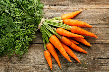 Bunch of tasty ripe juicy carrots on wooden table, top view