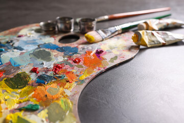Artist's palette, brushes and paints on grey table, closeup. Space for text