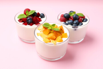 Tasty yogurt with fresh berries, fruits and mint in glasses on pink background, closeup