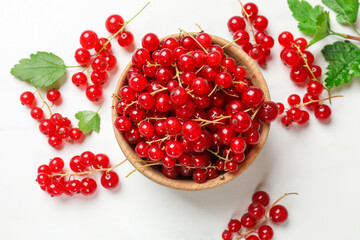 Fresh red currant berries in bowl on white table, top view