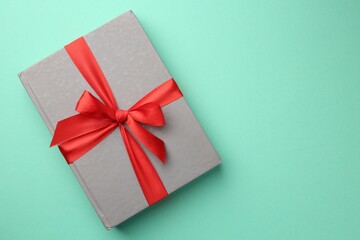 Book tied with red ribbon on green background, top view with space for text. Perfect gift