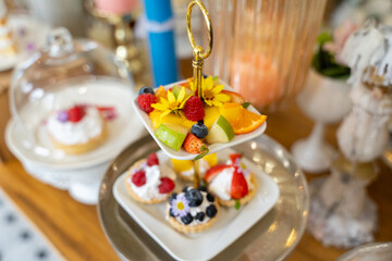 Sweet Celebration: A two-tiered dessert stand adorned with fresh fruit and flowers takes center stage at a delightful gathering.