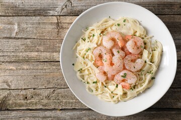 Delicious pasta with shrimps and cheese on wooden table, top view. Space for text