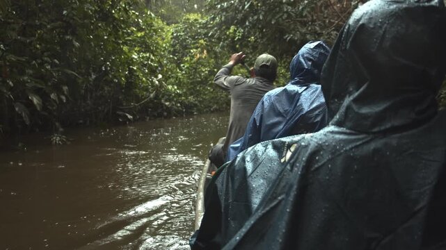 Tourist take a boat through a stunning narrow river through the jungle as it rains