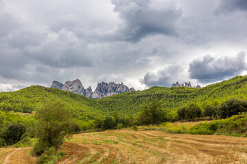 Fototapeta premium Campos de cultivo junto a bosques y montaña de Montserrat un día nublado y tormentoso