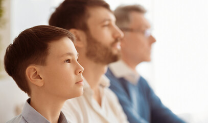 Fototapeta premium Growing Up. Family Portrait Of Boy, His Father And Grandfather Sitting Together At Home. Side View, Shallow Depth