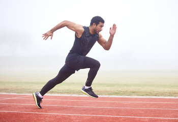 Outdoor, fitness and man running at track for sports, exercise and practice for competition. Fog, mist and Asian male athlete with speed at athletics field for workout, cardio and training for race