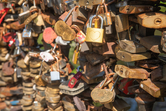 background of fence on bridge filled with metal closed love locks of couples 