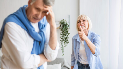 Senior couple having relationship problems, quarrelling at home. Woman shouting at man