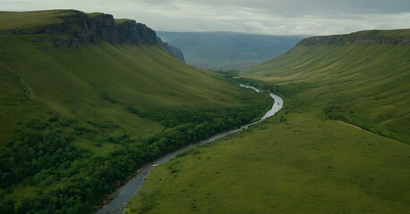 Fototapeta premium River flowing through lush green valley surrounded by cliffs