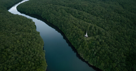 Small church building surrounded by forest and river, aerial view