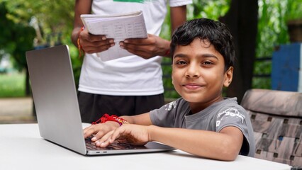 Indian School kids E-learning using laptop. Children doing homework at garden in computer.