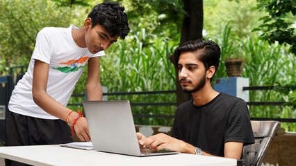 Indian School kids E-learning using laptop. Children doing homework at garden in computer.