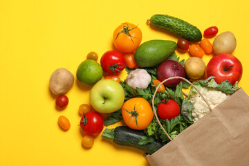 Delivery of vegetarian products. Paper bag with different vegetables and fruits on yellow background, top view © New Africa