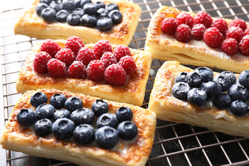 Tasty puff pastries with berries on grey table, closeup