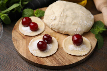 Process of making dumplings (varenyky) with cherries. Raw dough and ingredients on wooden table