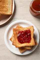 Delicious toasted bread slices served on wooden table, flat lay