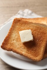 Delicious toasted bread slices with butter on table, closeup